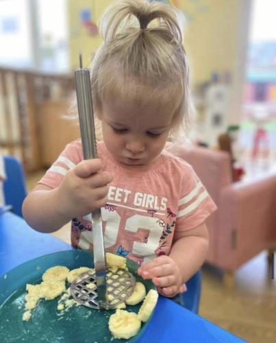 Mashing bananas to make healthy yogurt bites at Gower Day Nursery